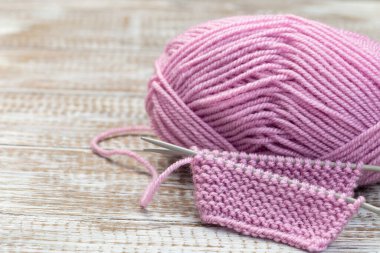 İğneli örgü parçası ve ahşap arka planda pembe iplik kesesi, yatay, kopya alanı