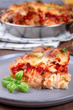 Köfteli makarna, mozarella, domates sosu ve fesleğen, gri tabakta, dikey.