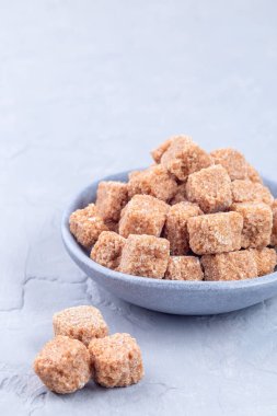 Kahverengi şeker ya da kamış şekeri kasede ve gri arkaplanda dikey, kopyalama alanı