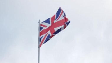 British flag waving in wind on gray sky background, Union Flag or Union Jack. High quality 4k footage