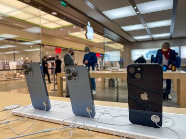 Köln, Almanya - 1 Ekim 2021: Yeni iPhone 13 'ün yanı sıra iPhone 13 Pro ve iPhone 13 Mini' yi Apple Store 'da karşılaştıran ve test eden bir Alman fotoğrafçı.