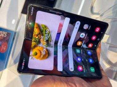 Köln, Almanya - 30 Eylül 2021: Bir Alman fotoğrafçı, yeni Samsung Galaxy Fold 5G modellerini Satürn 'deki elektronik pazarında izleyerek bir alışveriş malını ziyaret ediyor.