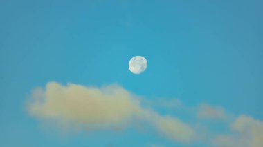 Bulutlarla kaplı mavi gökyüzünde sabah ayı