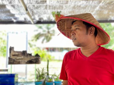 Portrait young man wearing red shirt and traditional hat from bamboo