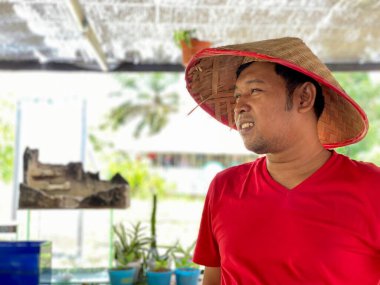 Portrait young man wearing red shirt and traditional hat from bamboo