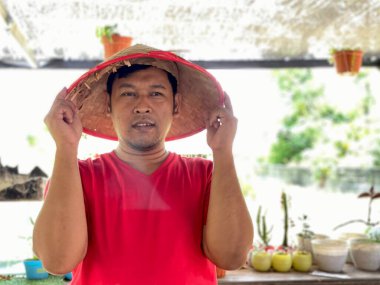 Portrait young man wearing red shirt and traditional hat from bamboo