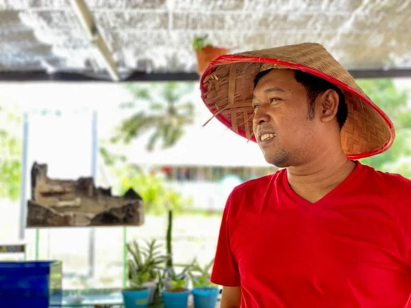 Portrait young man wearing red shirt and traditional hat from bamboo