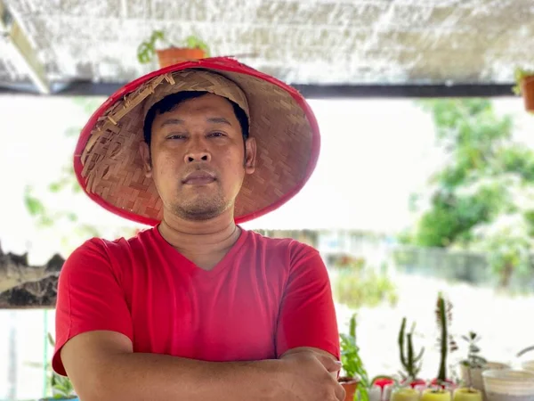 Portrait young man wearing red shirt and traditional hat from bamboo