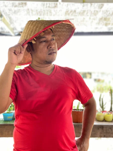 Portrait young man wearing red shirt and traditional hat from bamboo