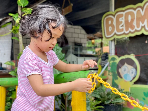 little girl playing with chain at the playground