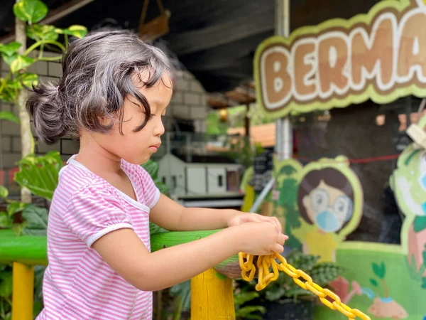 little girl playing with chain at the playground