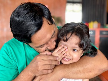 Father and daughter playing together at restaurant, enjoying togetherness