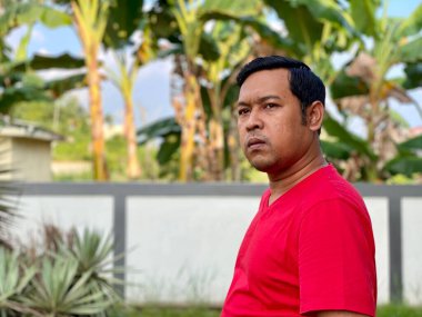 Young man in red shirt looking away