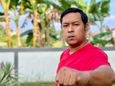 Young man in red shirt looking at camera showing high spirit