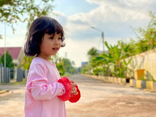 Evin ön bahçesinde oynayan pembe elbiseli şirin bir kızın portresi. Açık havada eğleniyoruz.