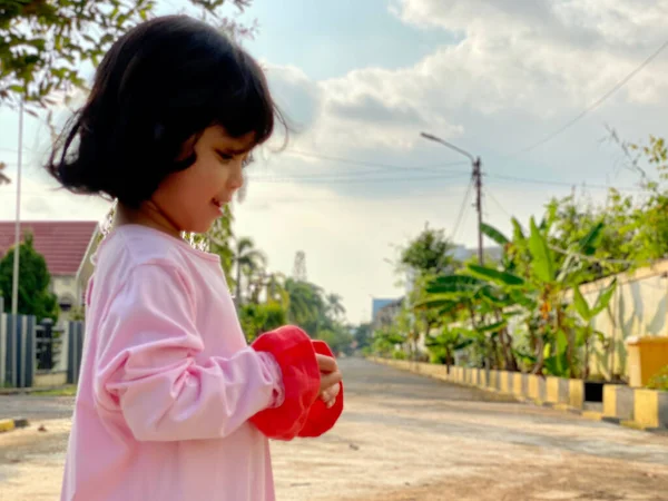 Evin ön bahçesinde oynayan pembe elbiseli şirin bir kızın portresi. Açık havada eğleniyoruz.