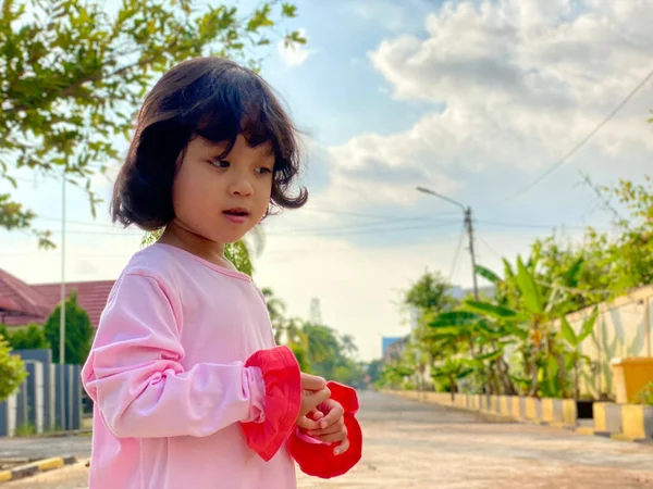 Evin ön bahçesinde oynayan pembe elbiseli şirin bir kızın portresi. Açık havada eğleniyoruz.