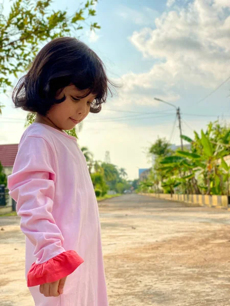 Evin ön bahçesinde oynayan pembe elbiseli şirin bir kızın portresi. Açık havada eğleniyoruz.