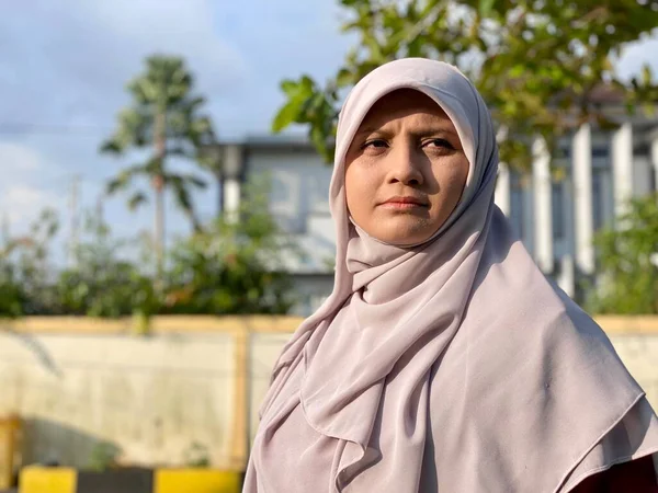 Başörtüsü takan genç, güzel bir kadın ve yüzünde mutlu bir ifadeyle kameraya gülümsüyor.