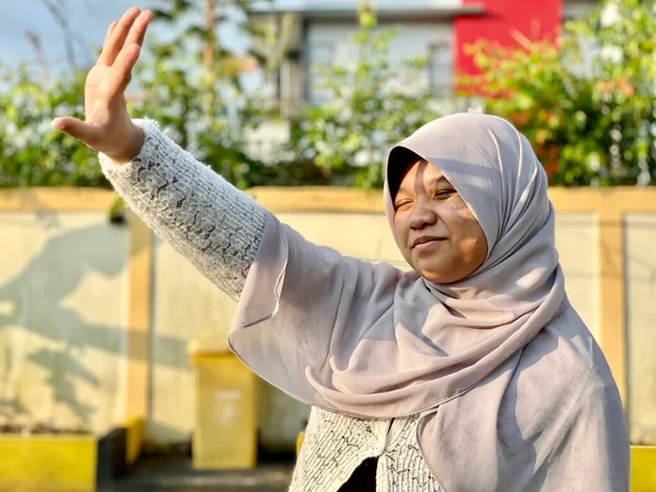 Öğlen güneşinden yüzünü örten tesettürlü genç bir kız.