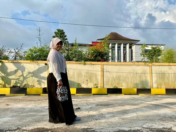 Ön bahçede duran tesettürlü genç kız.