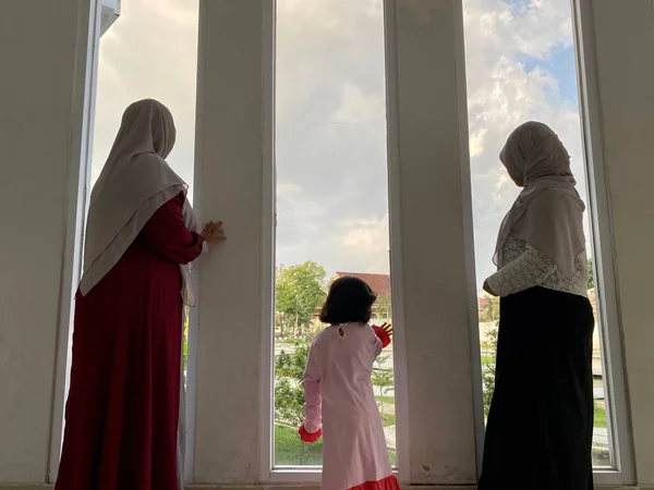 Mother and her child standing looking away through window in building