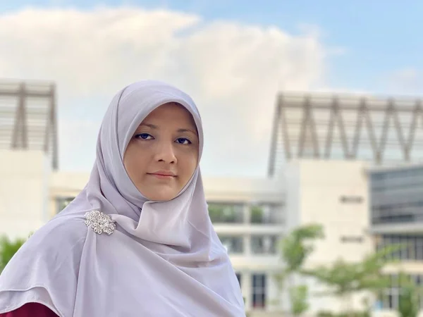 Young woman wearing hijab standing in the university park