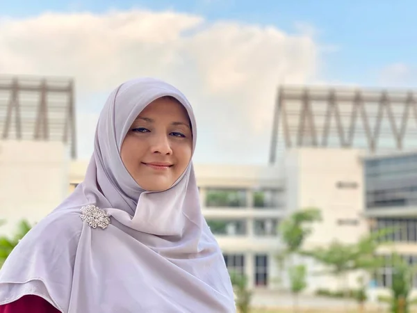 Young woman wearing hijab standing in the university park