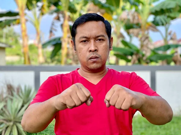 Young man in red shirt looking at camera showing high spirit