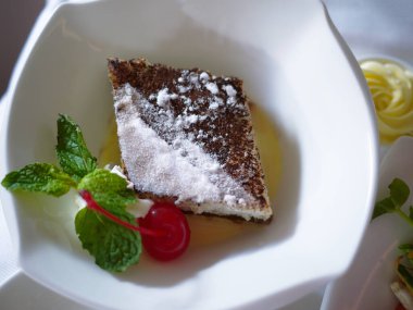 Eşkenar dörtgen şeklinde pasta kremasını kirazlı ve nane şekerli beyaz kaseli, yemek duvar kağıdıyla kapat.