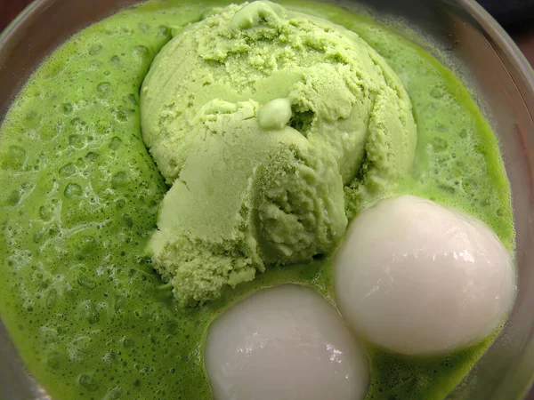 Close up Matcha green tea ice cream in matcha ice latte with 2 balls of mochi glutinous rice served in a glass bowl, famous Japanese matcha cafe