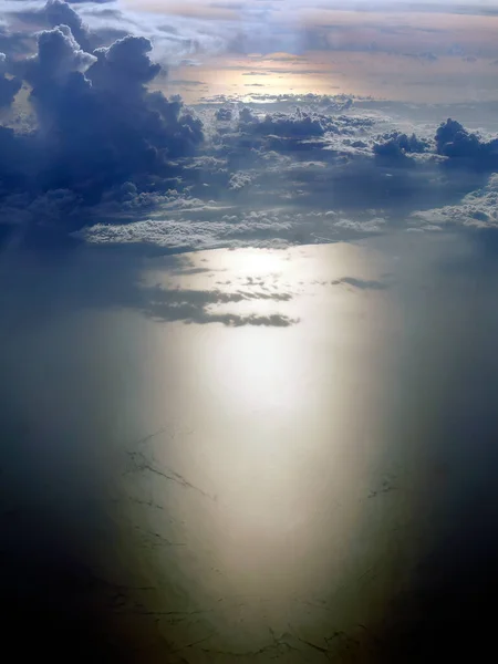 Aerial shot of sea water reflected warm sunset lights, cloudscape in the sky casting their shadow on the ocean, tranquil evening sky scene