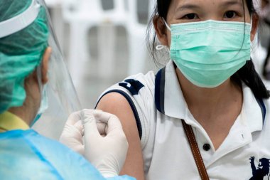 Bangkok, Tayland - 16 Ocak 2022: Asyalı doktor, Coronavirus 'tan koruyucu yüz maskesi takan hastaya omicron covid antiviral aşı takviyesi yapıyor..