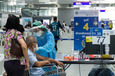 Bangkok, Tayland - 16 Ocak 2022: Asyalı doktor Bang Sue Grand İstasyonu 'nda koronavirüsünden koruyucu maske takan yaşlı bir hastaya covid antivirüs aşısı yapıyor..