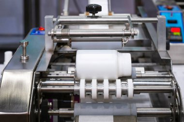 İlaç ve ilaç endüstrisi için küçük masa başı şişe etiketleme makinesi üzerinde beyaz plastik şişe.