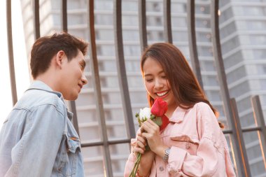 Genç mutlu çift ilk buluşmada aşk ve romantizm yaşar. Asyalı genç bir kadın sevgilisine sürpriz yapar ve sevgililer gününde kırmızı gül verir. çift ve mutluluk konsepti.