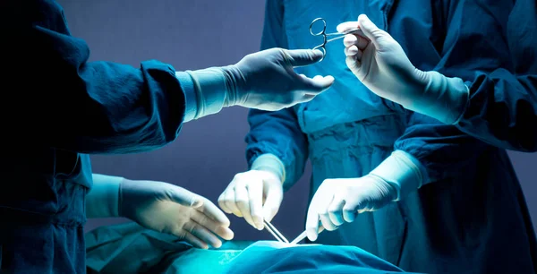 Doktor ve hemşire tıbbi ekibi hastanedeki acil serviste ameliyat yapıyor. Asistan ameliyat sırasında cerrahlara makas ve aletler dağıtıyor.