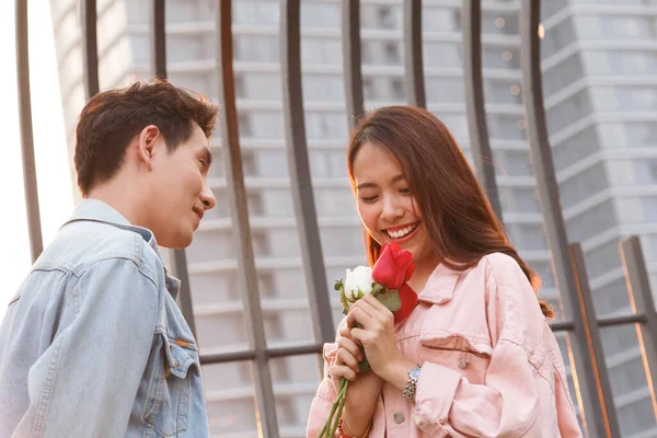 Genç mutlu çift ilk buluşmada aşk ve romantizm yaşar. Asyalı genç bir kadın sevgilisine sürpriz yapar ve sevgililer gününde kırmızı gül verir. çift ve mutluluk konsepti.