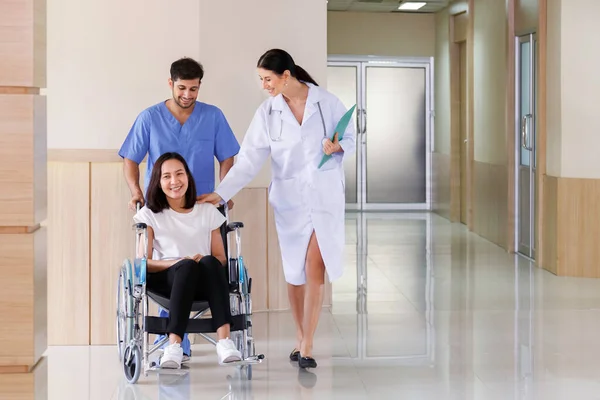 Mutlu gülümseyen Asyalı hasta kadın, erkek hemşireyle birlikte tekerlekli sandalyede oturuyor. Hastanedeki ameliyat planından sonra doktorla konuşuyor. Sağlık ve Tıp Konsepti