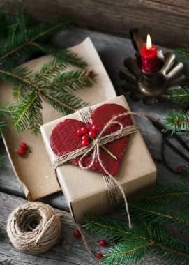 Noel hediyesi olarak ev yapımı kalp şeklindeki tebrik kartı ve koyu kırsal ahşap arka planda köknar dalları olan romantik dekoratif hediye kutusu..