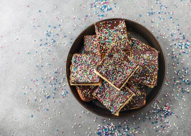 Doğum günü veya parti için tabakta çikolata kremalı ve renkli şekerlerle kaplı ev yapımı pasta. Süper manzara. Boşluğu kopyala. 