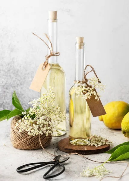 Homemade elderflower syrup in glass bottles for summer drink with elder flower buds and lemon. Organic drinks concept. Selective focus.