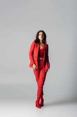 Kırmızı çizmeli, takım elbiseli, gri elbiseli, modaya uygun genç bir kadın.