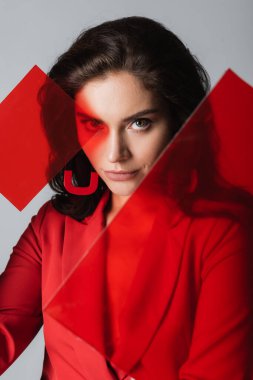 Güzel esmer kadın, gri camların yakınındaki kameraya bakıyor.