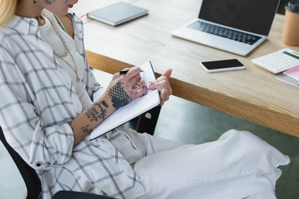 Corte Vista Tatuado Empresária Escrevendo Notebook Perto Gadgets Com Tela — Fotografia de Stock