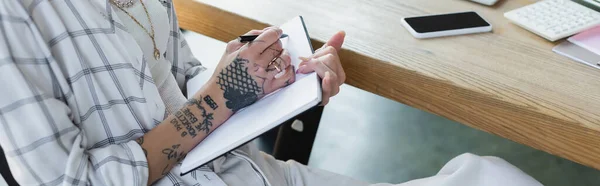 Bijgesneden Weergave Van Getatoeëerde Vrouw Schrijven Notebook Buurt Van Smartphone — Stockfoto