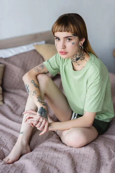 Ung Tatuerad Kvinna Sitter Sängen Hemma Och Tittar Kameran — Stockfoto