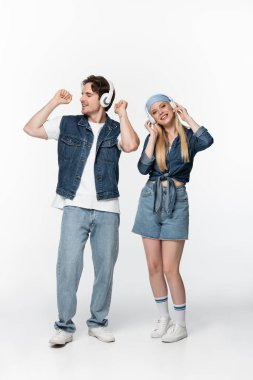 Moda ve neşeli çiftin kablosuz kulaklıklarıyla beyazdan müzik dinlerken tam boy görüntüsü