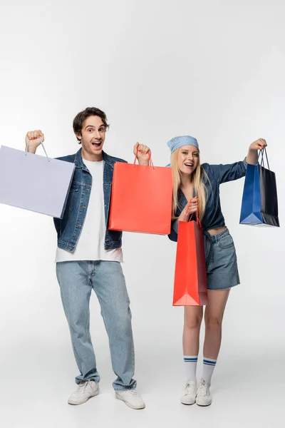 Happy Amazed Couple Denim Clothing Showing Multicolored Shopping Bags White — Stock Photo, Image