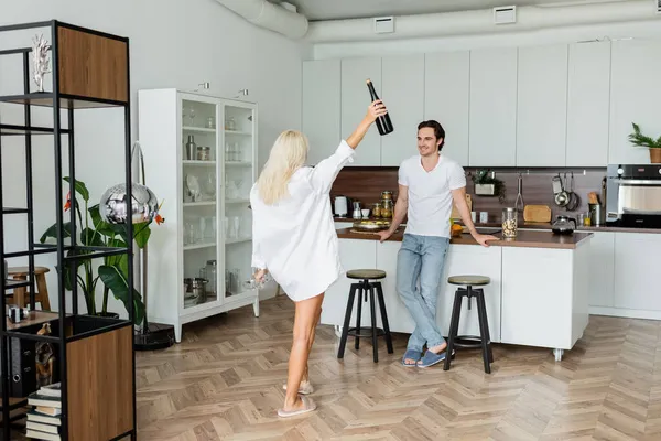 Hombre Alegre Mirando Mujer Rubia Con Botella Vino Vasos Cocina — Foto de Stock